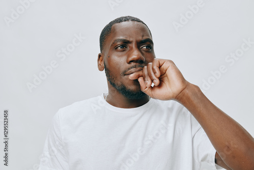 Foto Pensive young man in a white t shirt, deep in thought, against a light gray back