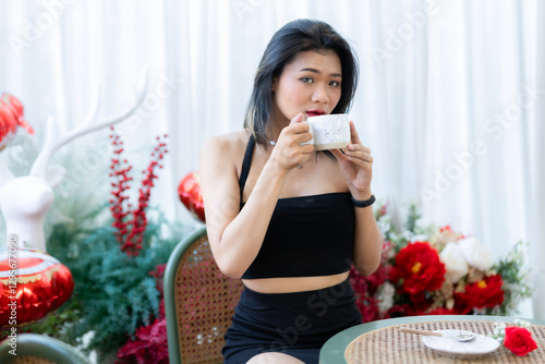 valentine's day, Portrait beautiful asian people woman fashion model in summer Black dress and coffee in cup holding bouquet of red roses in the living room inside or cafe