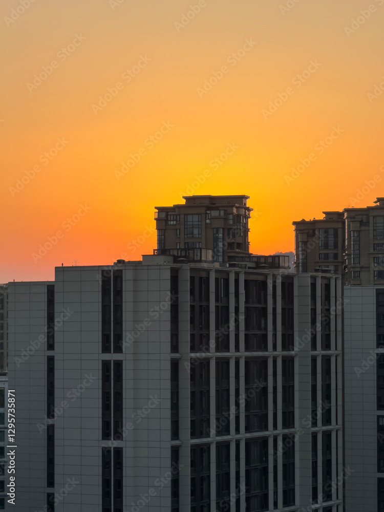 Beautiful sunset over modern buildings in an urban landscape showcasing vibrant orange and yellow tones near dusk Beautiful sunset over modern buildings in an urban landscape showcasing vibrant orange and yellow tones near dusk