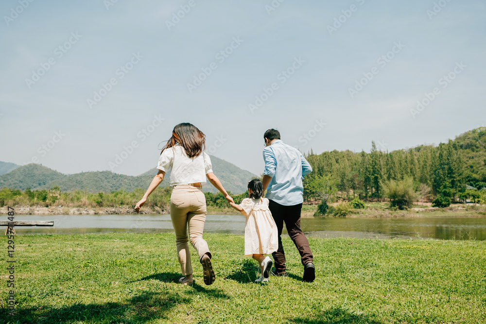 Asian family father mother and daughter holding hands and running lake in park, lifestyle parents and child kid enjoying outdoors together in nature on summer travel, Family relaxation, Back view Asian family father mother and daughter holding hands and running lake in park, lifestyle parents and child kid enjoying outdoors together in nature on summer travel, Family relaxation, Back view