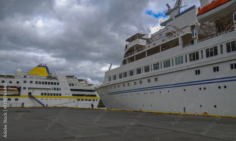 Naklejka premium Classic expedition cruiseship cruise ship liner Delphin and Hamburg docked at pier in Isafjordur, Iceland with harbor skyline and fjord landscape in background on during Arctic Circle summer cruising
