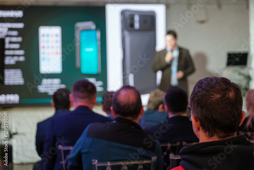Wallpaper Mural Audience listening to speaker during business presentation featuring latest smartphone technology with display screens Torontodigital.ca