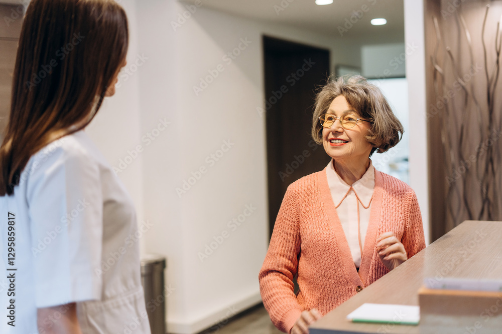 Senior woman talking with receptionist in medical clinic Senior woman talking with receptionist in medical clinic