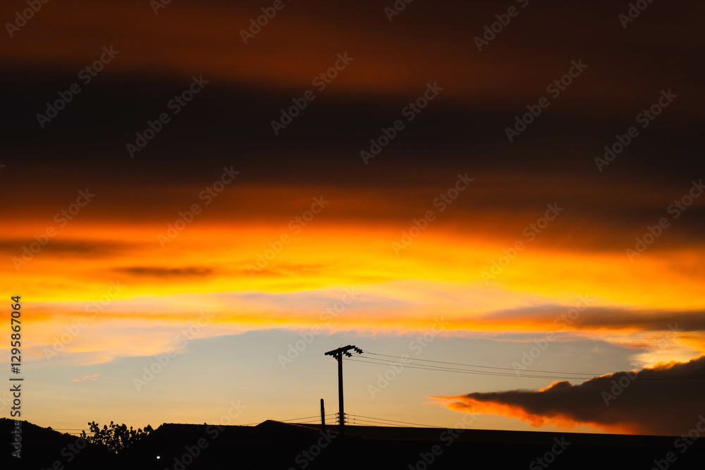 Naklejka premium Golden moody clouds by the rays of the dawn sun after sun has just set behind.