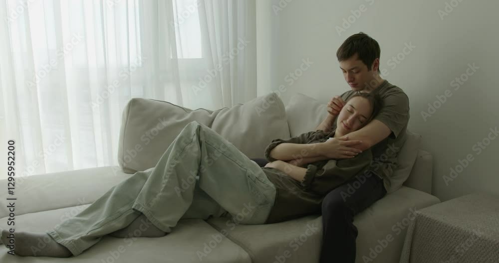 A couple relaxes on a comfortable couch, embraced warmly as they share an intimate moment. A couple relaxes on a comfortable couch, embraced warmly as they share an intimate moment.