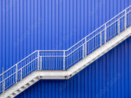 A galvanized steel stairs against a blue metal wall