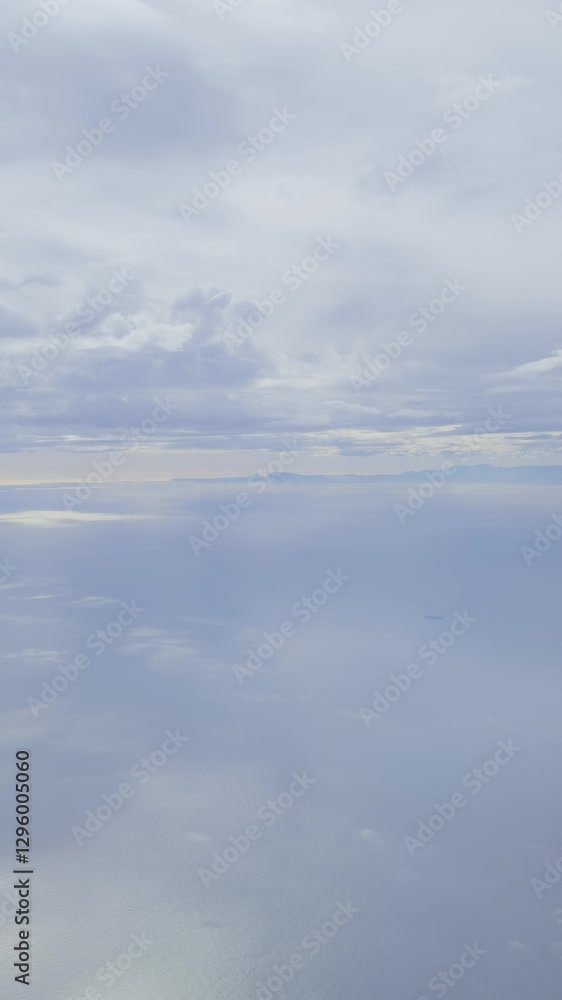 Soft, aerial view of calm, vast ocean and cloudy sky from an airplane window Soft, aerial view of calm, vast ocean and cloudy sky from an airplane window