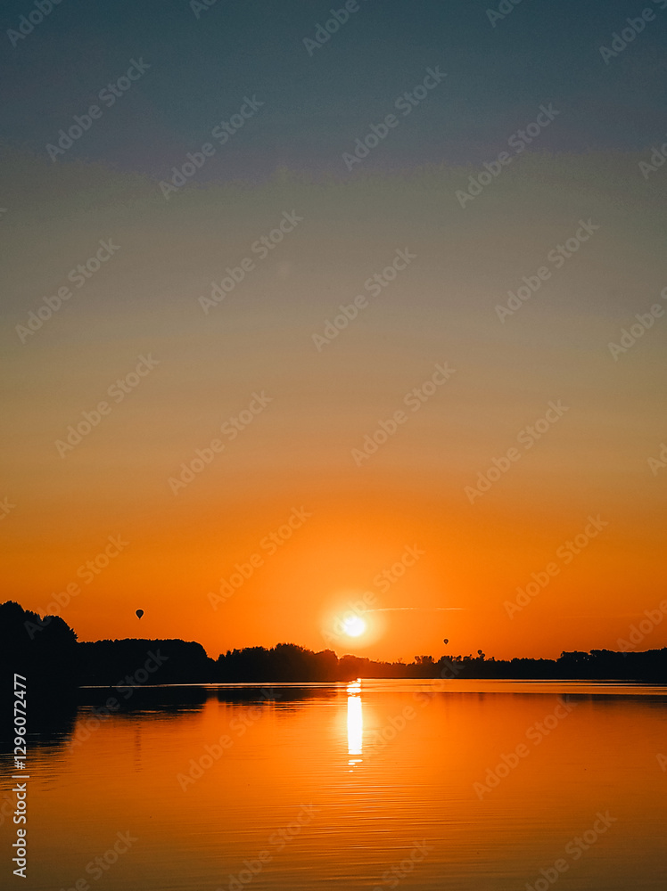 Naklejka premium A beautiful sunset over the sea. The setting sun over the sea. Hot air balloons taking off over the water at sunset.