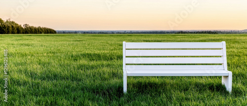 Minimalist funeral service. White bench in a green field during sunset.