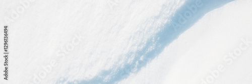 Wide panoramic winter background with snowy ground. Natural snow texture. Wind sculpted patterns on snow surface. Closeup top view with copy space.