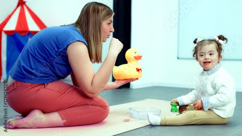 Nonverbal child with Down syndrome learning baby sign language with the help of a speech therapist. Child therapy, neurodiversity, learning difficulty, developmental disability.