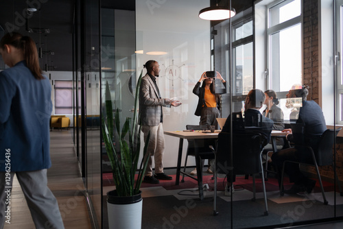 Diverse business team in a modern office discussing AI technology. A woman wearing a VR headset explores virtual reality, while colleagues engage in conversation. Concept of innovation and teamwork