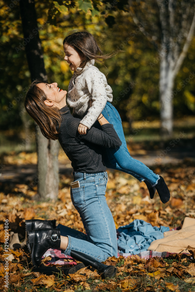 A mother and daughter play in an autumn park on a warm day. The concept of motherhood and joyful childhood emotions in an atmosphere of comfort and harmony. A mother and daughter play in an autumn park on a warm day. The concept of motherhood and joyful childhood emotions in an atmosphere of comfort and harmony.