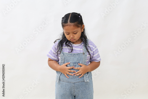 Little asian girl standing holding stomach pouting feeling hungry