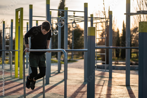 Obraz na plátně young athletic man exercising fitness calisthenics workout and making dips at st