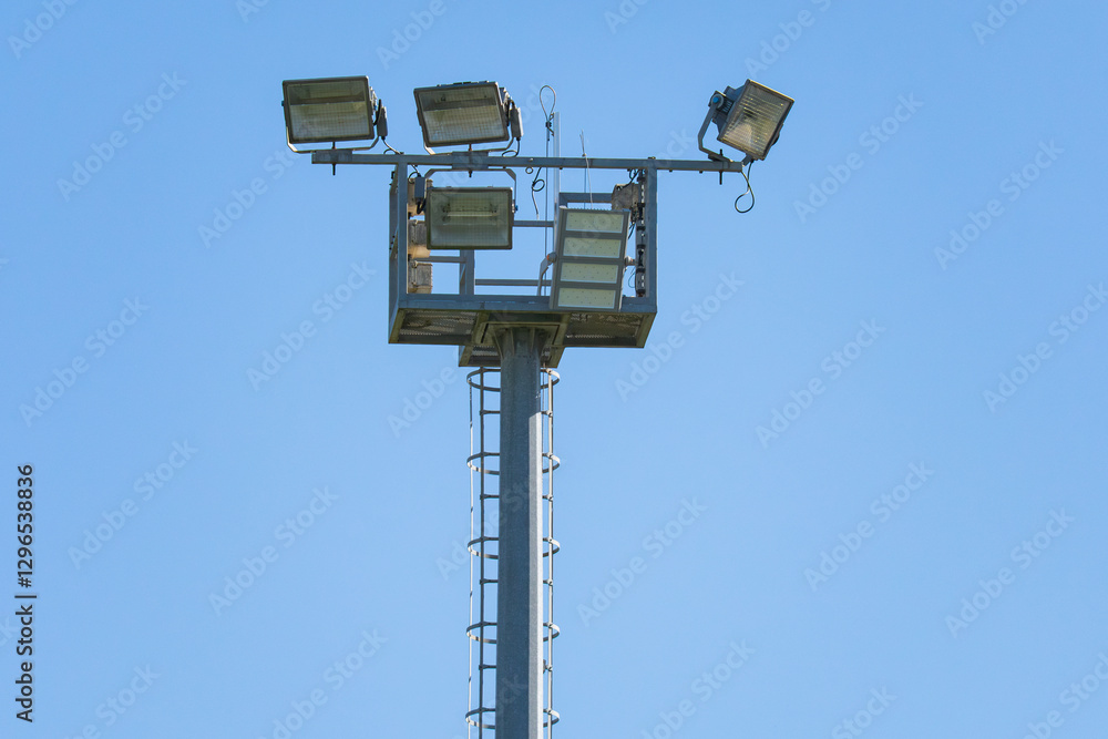 Bright lights illuminate the field under a clear blue sky Bright lights illuminate the field under a clear blue sky