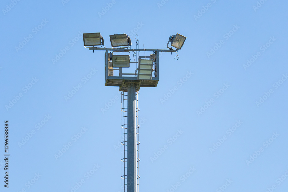Stadium floodlights illuminating a clear blue sky in daytime Stadium floodlights illuminating a clear blue sky in daytime