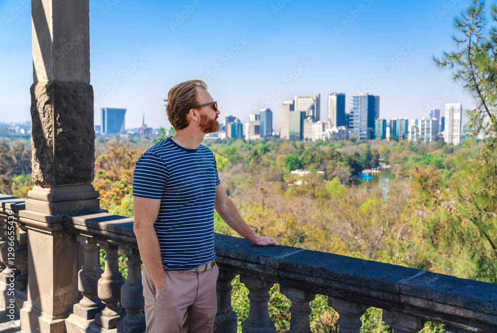 A tourist man standing at a terrace overlooking the Chapultepec Forrest and Mexico City skyscrapers
