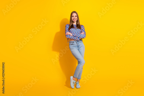 Fotografija Trendy young woman standing against a vivid yellow background, wearing a stylish