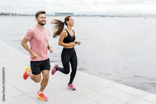 Slika na platnu Couple enjoys a morning run along the waterfront in a bustling city on a cloudy