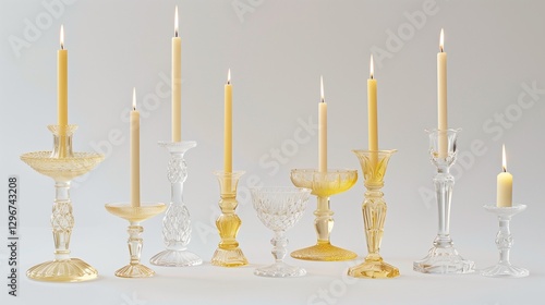 A set of vintage-style glass candleholders in varying heights, each holding a taper candle, displayed against a pure white background. 
