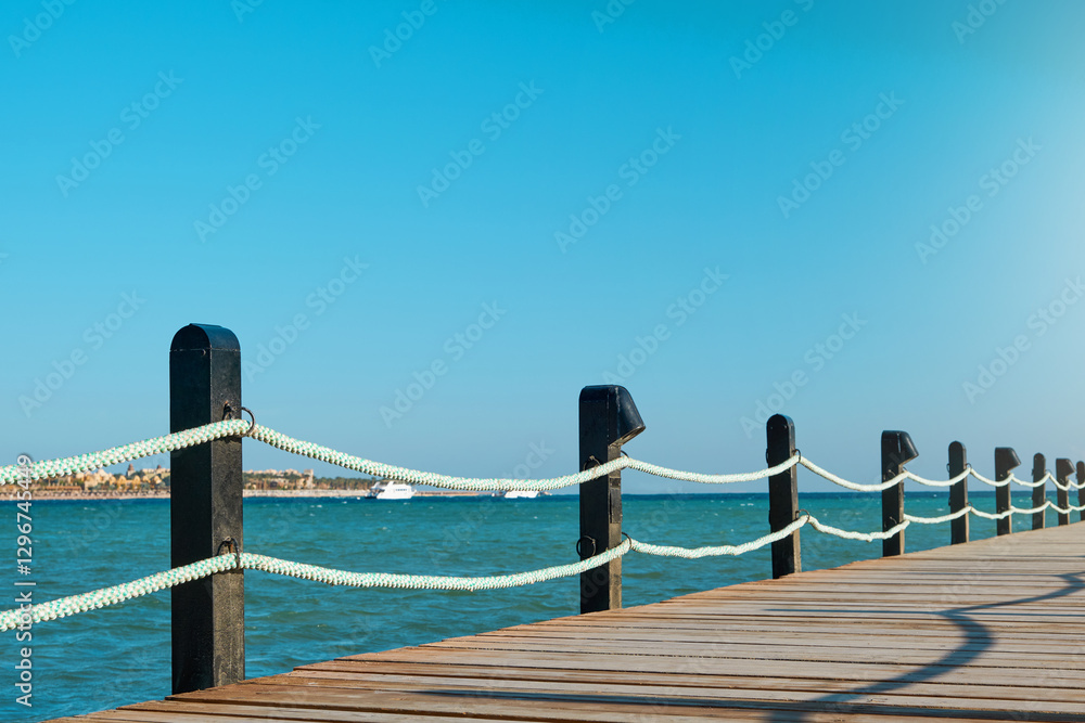 Obraz premium Wooden pier on sea stretching into distance beyond horizon on sunny summer day. Vacation and Travel Concept.
