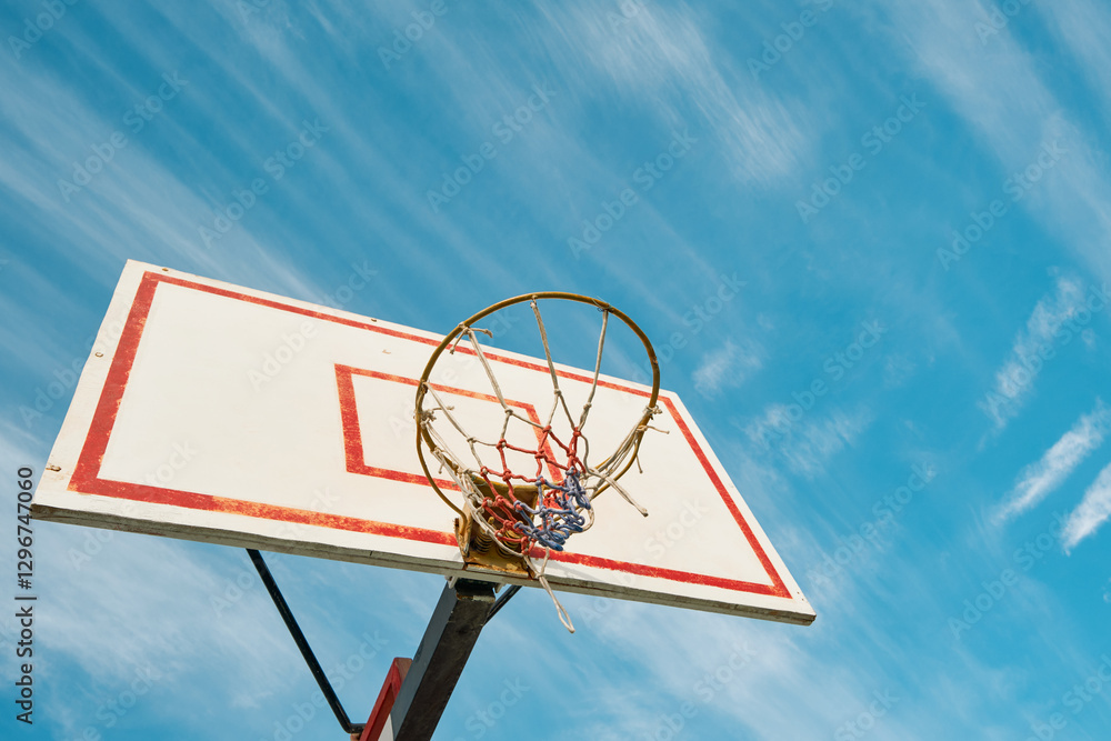 Old Basketball hoop on blue sky with clouds and sun glare on sunny day. Concept of success, scoring points and winning, healthy lifestyle, sports, Olympic movement, amateur sports. Copy space. Old Basketball hoop on blue sky with clouds and sun glare on sunny day. Concept of success, scoring points and winning, healthy lifestyle, sports, Olympic movement, amateur sports. Copy space.