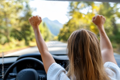A joyful woman throws her arms up in excitement while driving down a scenic road, enjoying the thrill of life and the beauty of nature surrounding her.