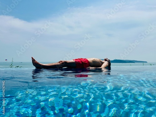Photography Homme en maillot de bain rouge dans une piscine débordante sur fond d'île en Malaisie