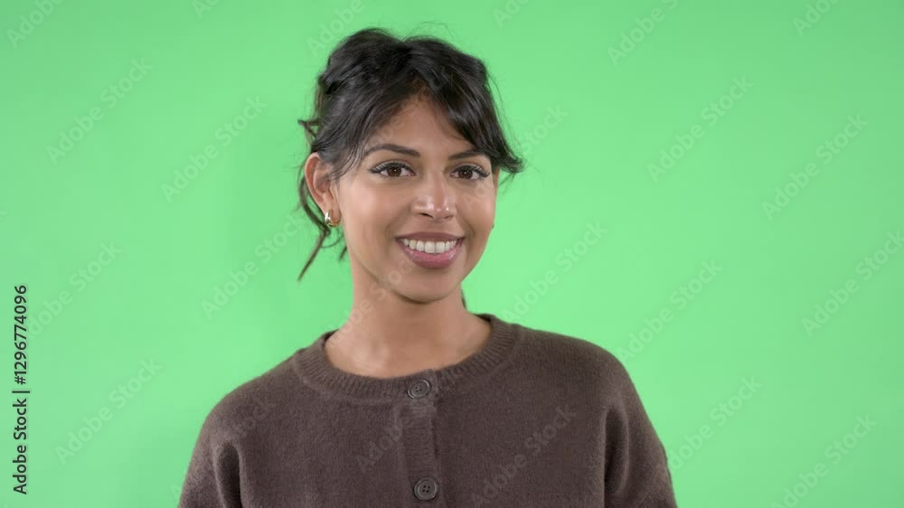 Cheerful woman smiling against bright green background in casual sweater during a fun photoshoot session Cheerful woman smiling against bright green background in casual sweater during a fun photoshoot session