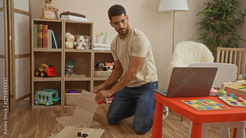 Handsome man assembling furniture in a cozy bedroom with toys and a cradle, surrounded by books, plants, and a laptop, indicating a warm family environment. Handsome man assembling furniture in a cozy bedroom with toys and a cradle, surrounded by books, plants, and a laptop, indicating a warm family environment.