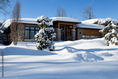 Modern house with evergreen trees buried in snow after intense snowstorms in Barrie Ontario suburb 2025