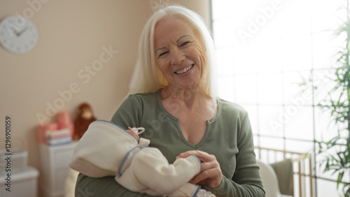 Woman smiling while holding baby in bedroom with cradle and clock visible in cozy indoor setting enhancing warmth and care.