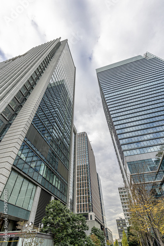 Canvas Print Low angle view of modern skyscrapers in tokyo business district with cloudy sky