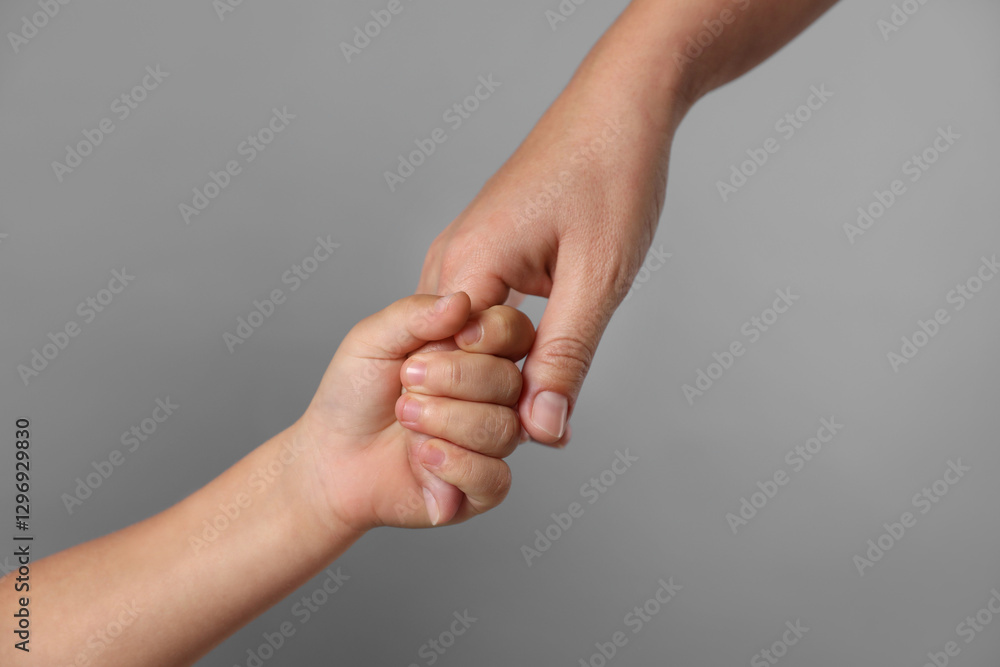 Mother and child holding hands on grey background, closeup Mother and child holding hands on grey background, closeup