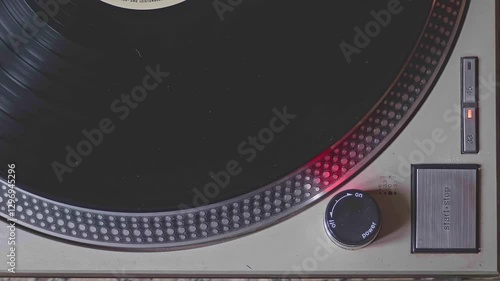 Close-up shot of a turntable being turned on and started. The needle drops onto a vinyl record, and the platter begins to spin.