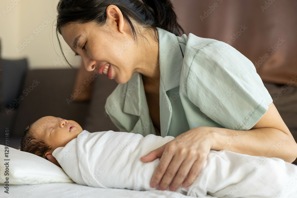 A woman is holding a baby and kissing its head. The baby is wrapped in a blanket. The woman is smiling and the baby is sleeping
A woman is holding a baby and kissing its head. The baby is wrapped in a blanket. The woman is smiling and the baby is sleeping
