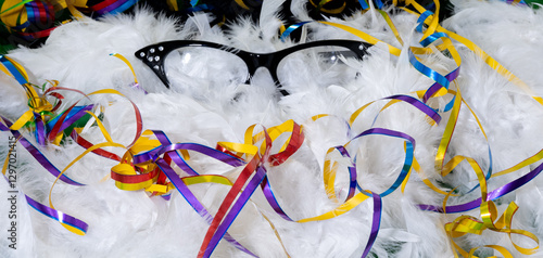 Black carnival glasses with colorful streamers on white feathers