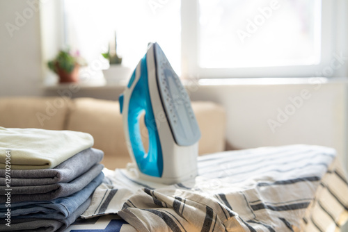 Electric iron and pile of clothes on ironing board