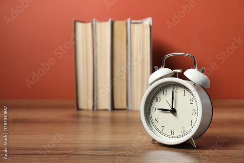 Fotografie Alarm clock and books on wooden table, space for text