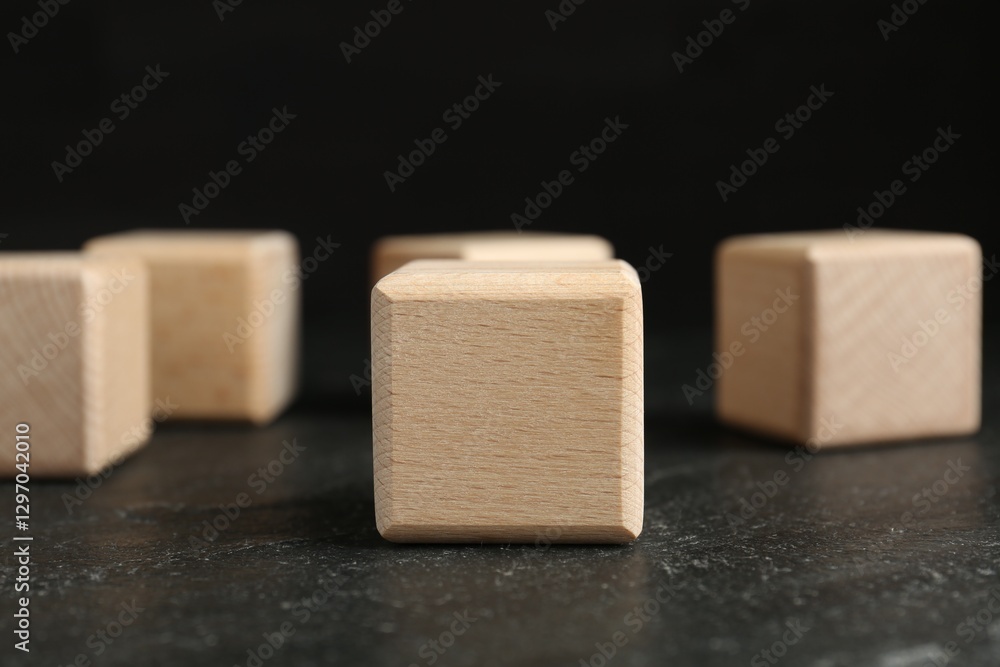 Blank wooden cubes on dark textured table against black background, closeup Blank wooden cubes on dark textured table against black background, closeup