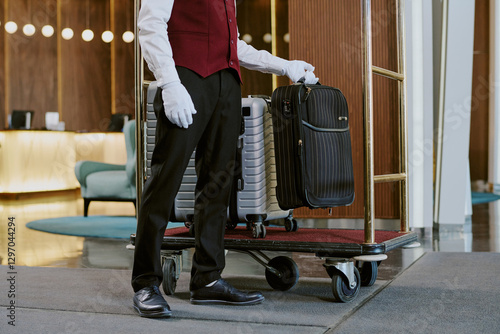 Obraz na płótnie Wide shot of unrecognizable male bellboy dressed in elegant uniform putting down