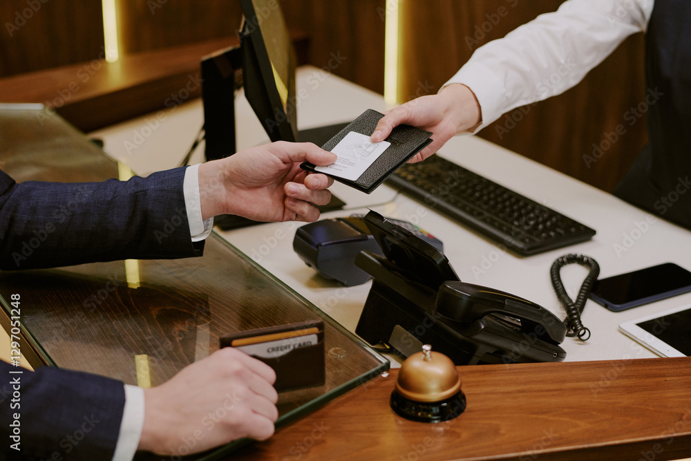 High angle shot of unrecognizable hand of guest and receptionist holding passport and room key above reception desk High angle shot of unrecognizable hand of guest and receptionist holding passport and room key above reception desk