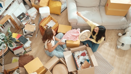 Obraz na płótnie Top view of happy friend unpacking box and picking furniture together