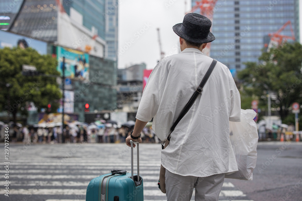 Japanese man with suitcase patiently waiting for the green light at a massive zebra crossing in Tokyo during light rain Japanese man with suitcase patiently waiting for the green light at a massive zebra crossing in Tokyo during light rain