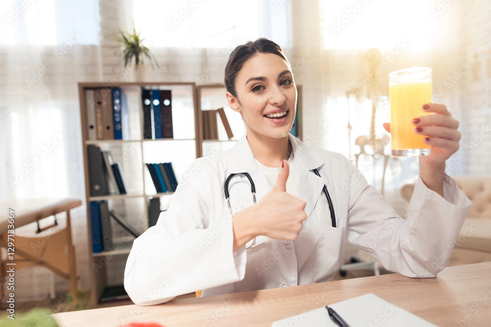 Female doctor sitting at desk in office with microscope and stethoscope. Woman is holding juice. Female doctor sitting at desk in office with microscope and stethoscope. Woman is holding juice.