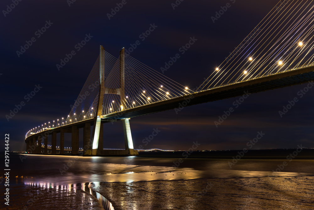 Obraz premium The illuminated Vasco da Gamma Road Bridge in the Portuguese capital Lisbon in the blue hour just before sunrise.