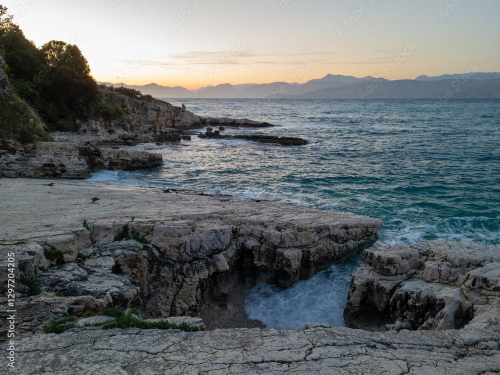 Coastal cliffs meet turquoise water at sunset, with mountains in the distance and natural rock bridges. Coastal cliffs meet turquoise water at sunset, with mountains in the distance and natural rock bridges.