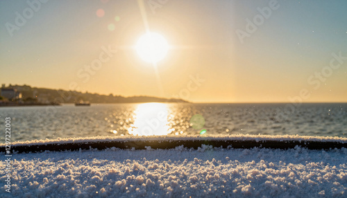 Frost-covered hood reflecting sunlight over tranquil sea at dawn, serenity photo