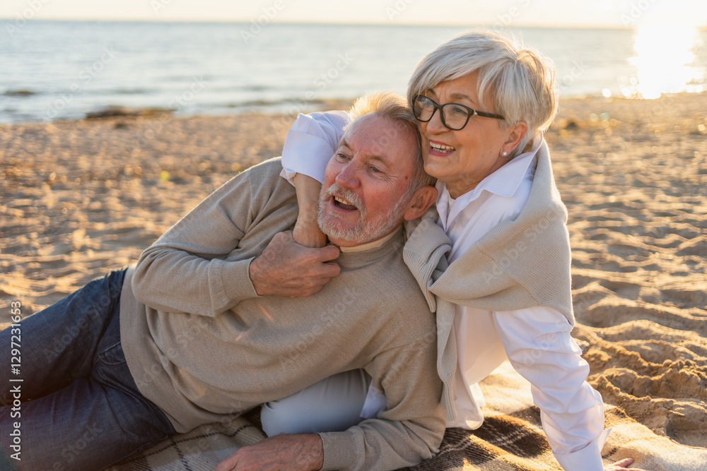 Obraz premium Senior mature couple sitting on beach hugging enjoying outdoor recreation. Old husband wife embracing with tenderness love enjoying sweet bonding. Grandmother grandfather together. Family moment love